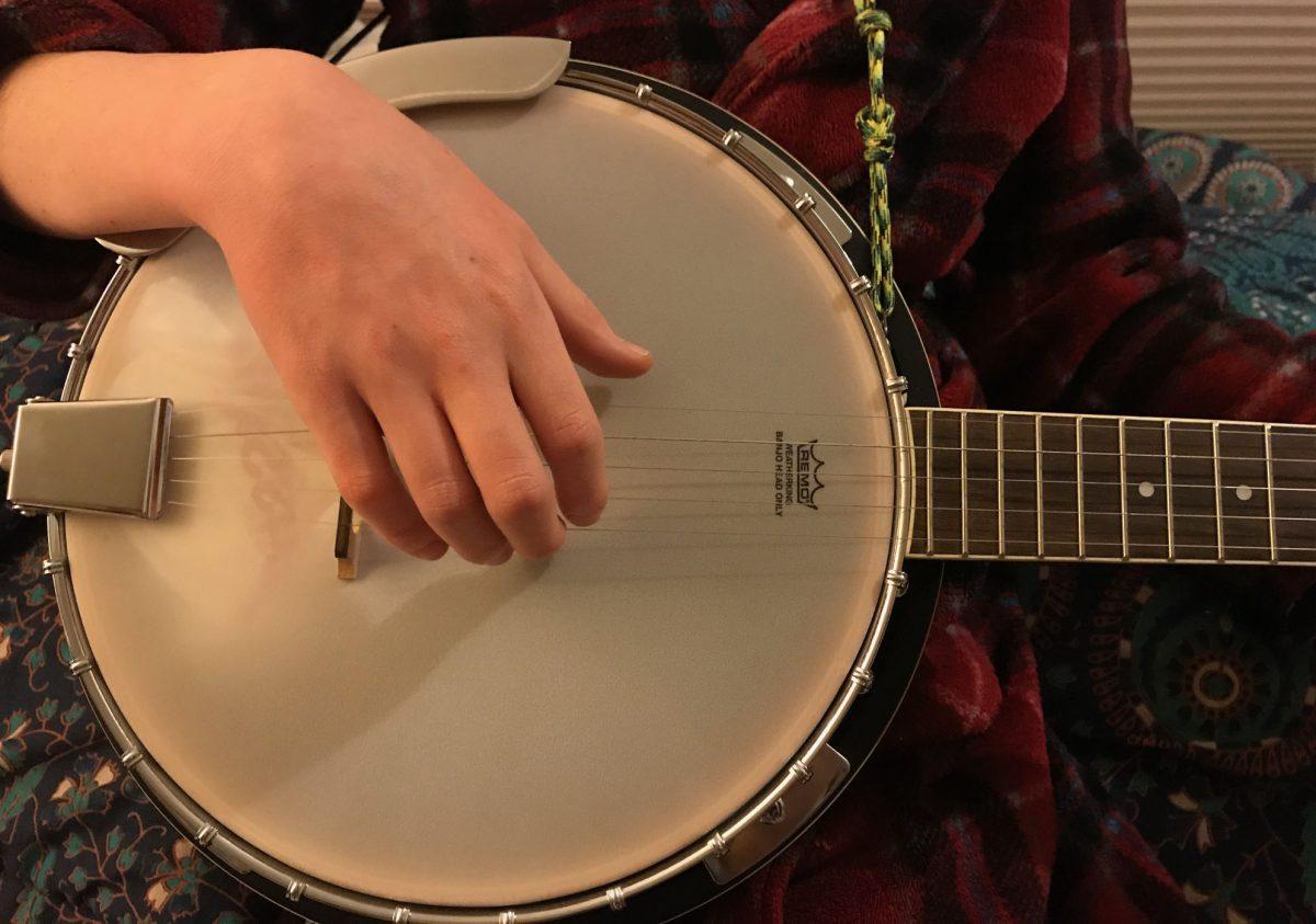 A young boy strums a banjo. The banjo has a complicated history. Photo by Annika Mayne.