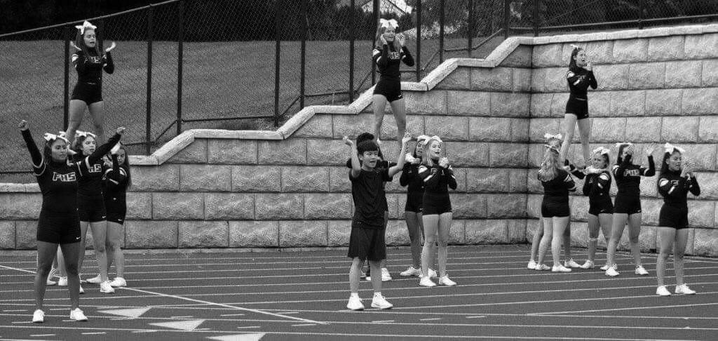 David Hoang (11) cheers with his teammates at a football game earlier this school year. Hoang is one of two male cheerleaders on Franklin’s team. Photo by Mari Dika.