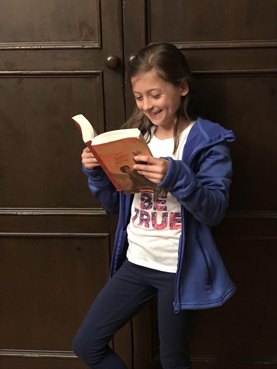 Glencoe Elementary student Ella Knecht reads a well-used copy of a Harry Potter book. The series has captivated young readers since its release in 1997. Photo by Sadie Tresnit.
