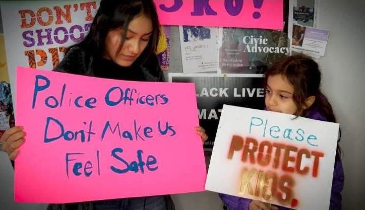 Jefferson High School senior Sophia Lucas and her younger sister hold signs advocating against the new School Resource Officer Intergovernmental Agreement. Lucas has been one of the leading student voices in opposition to the IGA. Photo by: Micheal Hull.