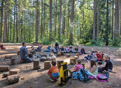 Students at the Portland Forest School gathered in a circle in the forest. This is what an average day at the outdoor education school looks like. Photo via Kate Mitchell.