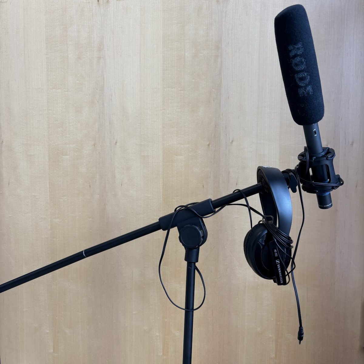 A microphone and pair of headphones hanging on the stand of the mic. The essential equipment for podcasting are these two items, but it’s important to keep in mind that “with great power comes with great responsibility.” Photo by 