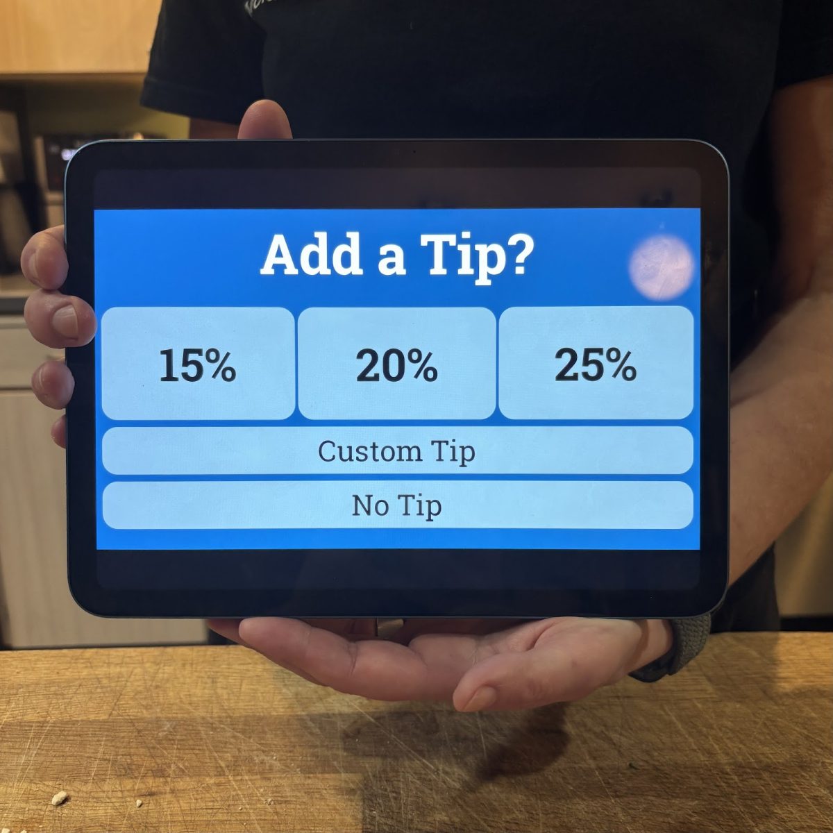 An employee holding up a tip screen, waiting for an answer. Do you tip your food service workers? Photo by 