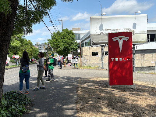 Protesters outside the Tesla dealership in Portland. Hostility towards Tesla CEO Elon Musk has led some to take action against his business in the form of demonstrations and occasionally vandalism. Photo by Shani Ross.