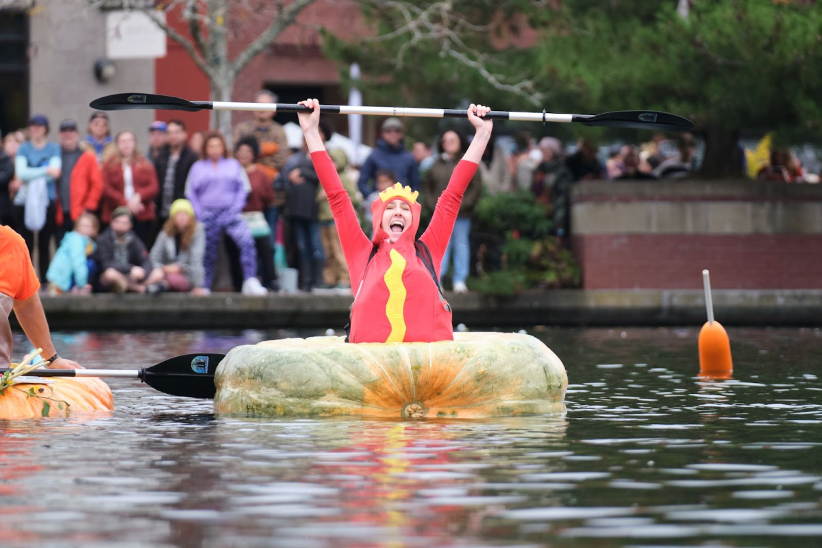Jessica Crawford, a racer at the 2023 West Coast Giant Pumpkin Regatta, raises her paddle in celebration of her third-place finish. The West Coast Giant Pumpkin Regatta is one of the biggest fall festivals in the Pacific Northwest. Photo by Evan Marx.