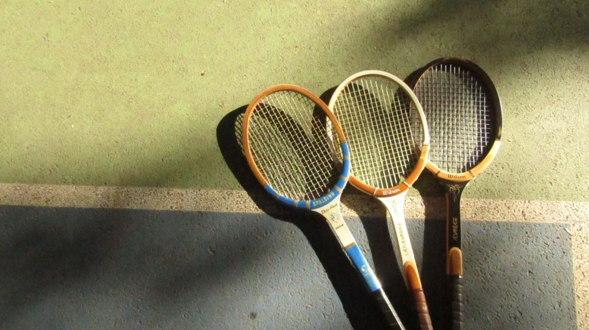 Three vintage tennis rackets lie on a tennis court. Though they, of course, use modern equipment, seniors living in Oregon participate in all kinds of sports, finding lifelong joy in athletics. Photo by Norah Dobrot.