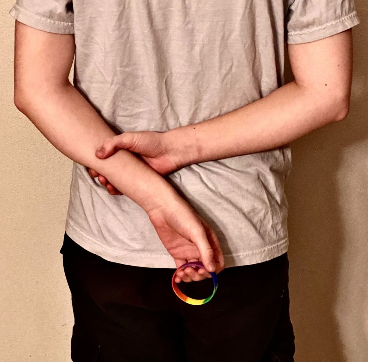 A person holds a pride-themed bracelet behind his back. Casual homophobia, though often unconscious, can still be harmful and reinforce prejudice. Photo via Lila MacKenzie.