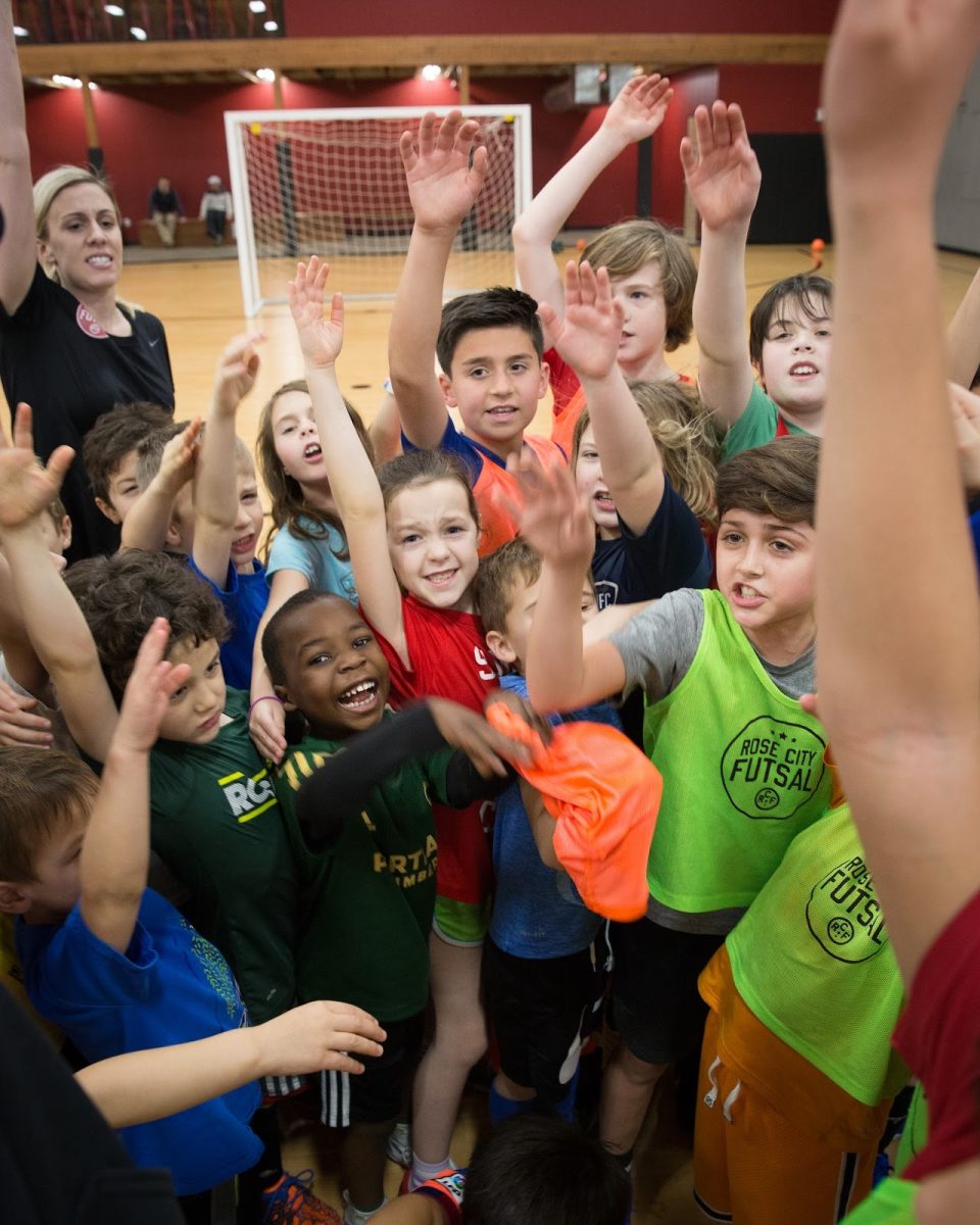 A group of elementary-aged children come together to cheer during a Rose City Futsal youth camp. Rose City Futsal hosts a variety of camps, tournaments, and leagues for athletes of all ages and skill levels. Photo via Joe Lescher