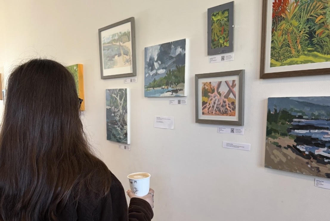 An Albina Press customer browsing art with coffee in hand. Many coffee shops in Portland have been incorporating art displays to brighten their spaces. Photo by Micah Dickinson.