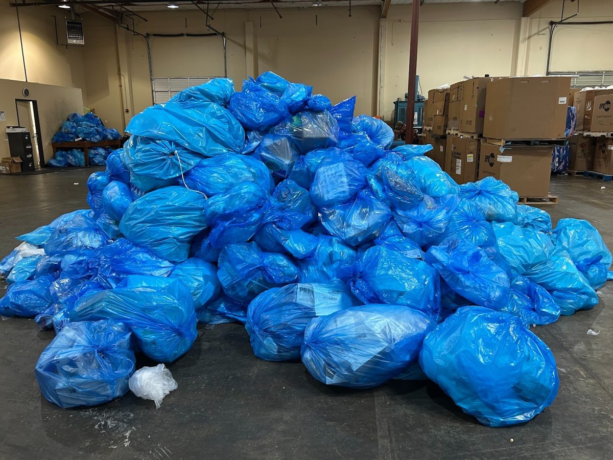 A pile of blue plastic bags inside of a warehouse, home of the Providence Recycling Program. In this space, plastics from six different hospitals are taken in, sorted, and recycled for other purposes.