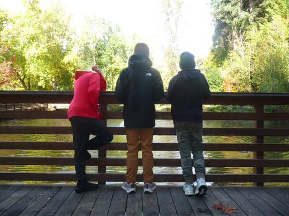 Three sixth grade students lean over a bridge at Camp Angelos Outdoor School (ODS). Through this program, many middle schoolers get the opportunity to connect with nature and make friends. Photo via Max Schneider.