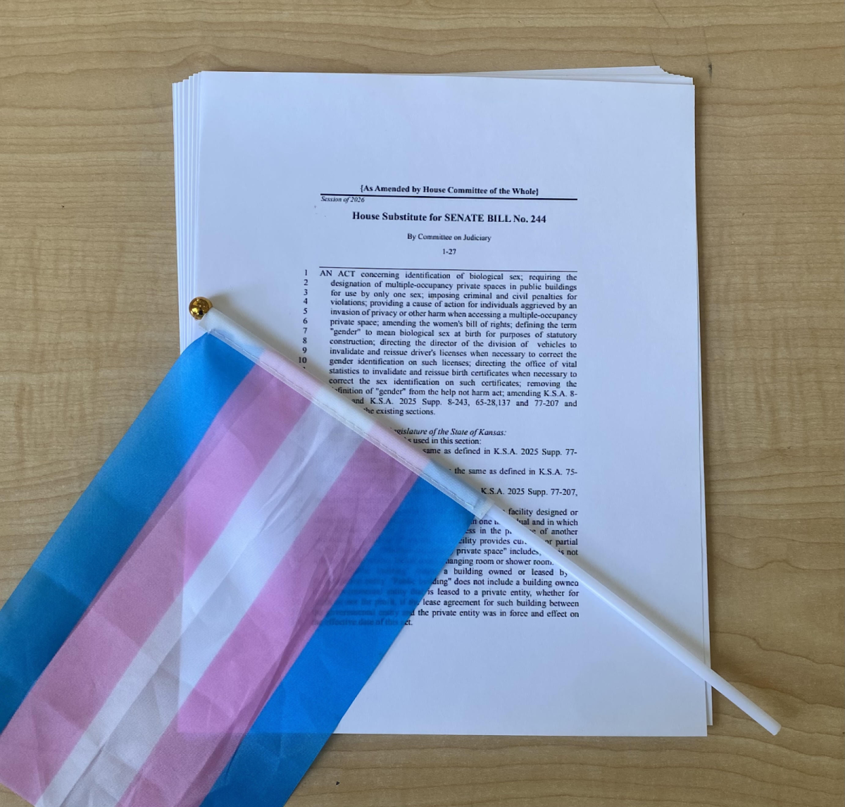 A transgender pride flag atop a printed copy of Kansas Senate Bill (SB) 244. SB 244 restricts bathroom access for transgender people in government buildings and invalidates all driver’s licenses with a gender marker that has been changed. Photo by Rusty MacKenzie.